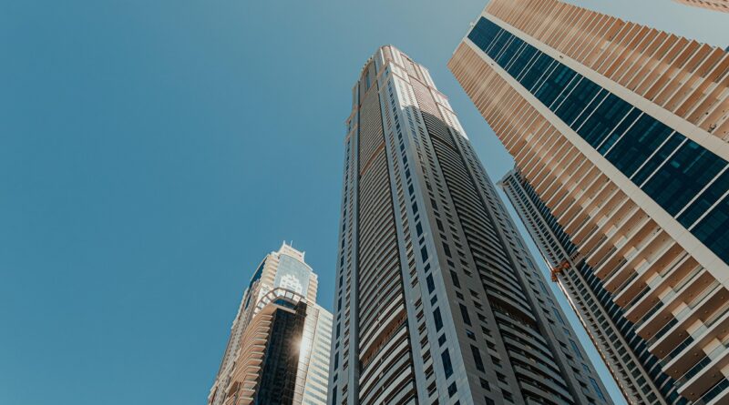 architectural design, architecture, business district, city, city center, cityscape, clear blue sky, corporate buildings, financial district, glass facades, high-rise buildings, high-rises, modern buildings, modern construction, modern metropolis, office buildings, residential towers, skyscrapers, tall towers, tower block, upward view, urban architecture, urban infrastructure, vertical architecture